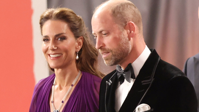 A smiling Princess Catherine standing next to a serious-looking Prince William in their finery