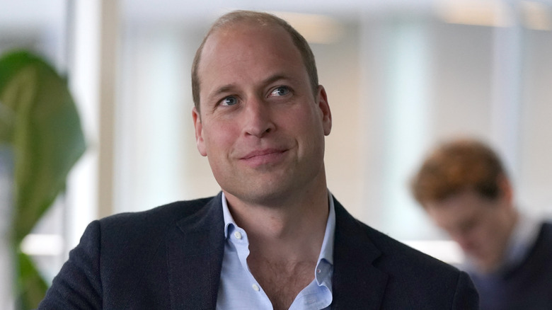Prince William smiles while seated at a table