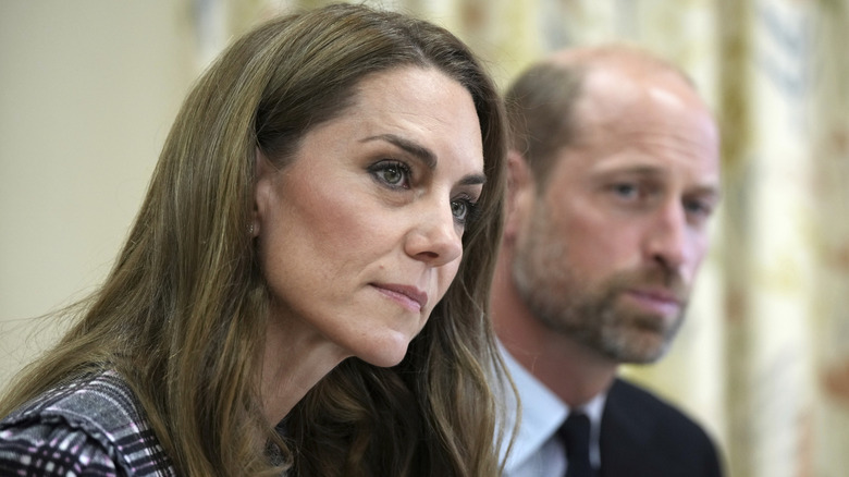 Kate Middleton sitting beside Prince William while both listen to someone speak