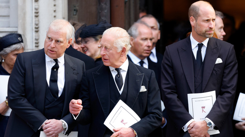 Prince Andrew and King Charles III speaking as Prince William looks away