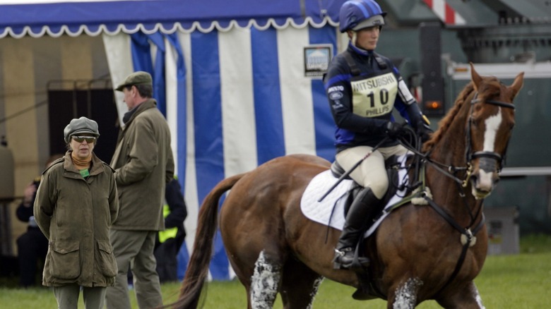 Princess Anne standing behind Zara Tindall's horse