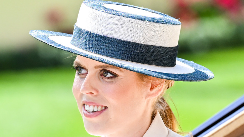 Princess Beatrice smiling in a white and blue hat.