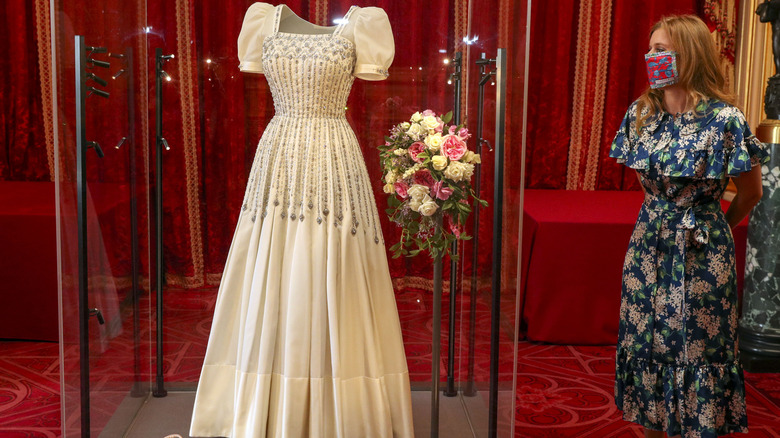 Princess Beatrice wearing a mask and looking at her wedding dress.