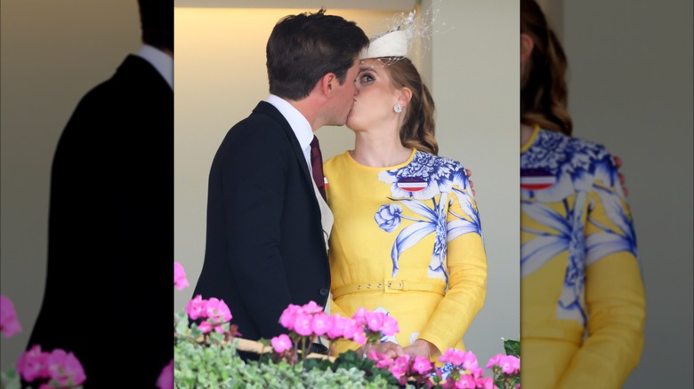 Princess Beatrice wearing a yellow dress while kissing Edoardo Mapelli Mozzi who's wearing a suit.