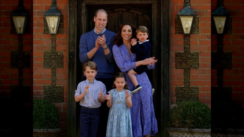 The Wales family outside their home clapping