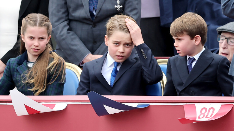 Princess Charlotte, Prince George, and Prince Louis sitting together at an event looking totally over it