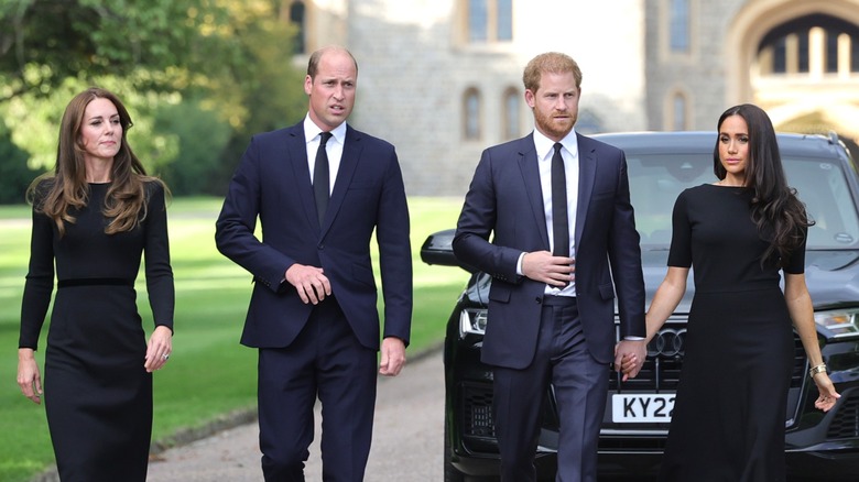 Kate Middleton, Prince William, Prince Harry and Meghan Markle in matching navy and black formal outfits.