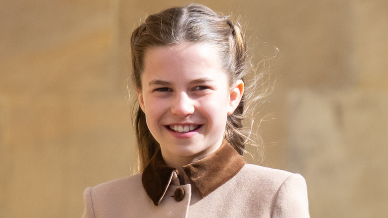 Princess Charlotte smiles in a tan coat.