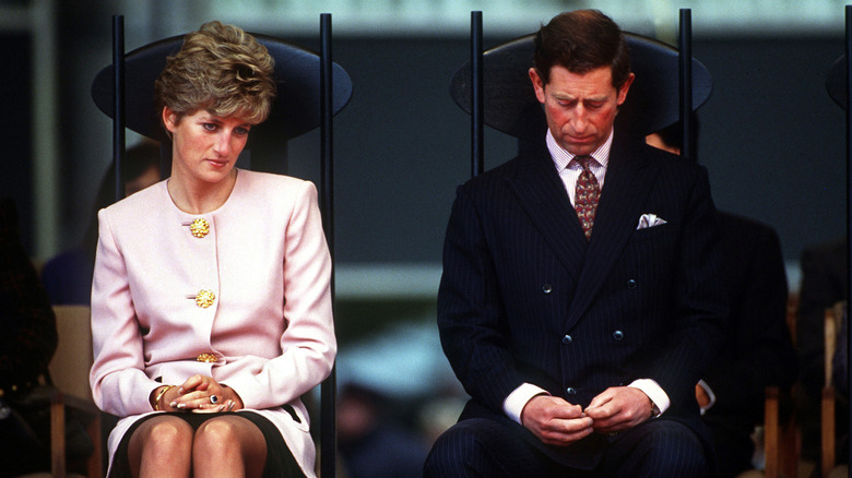 Princess Diana and then-Prince Charles sitting in separate chairs looking downward