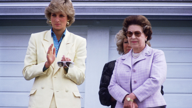 Princess Diana clapping beside Queen Elizabeth II.
