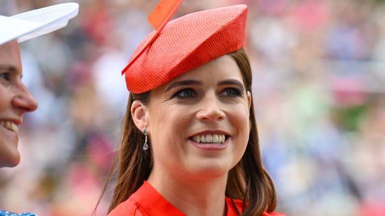 Princess Eugenie smiling in a red fascinator