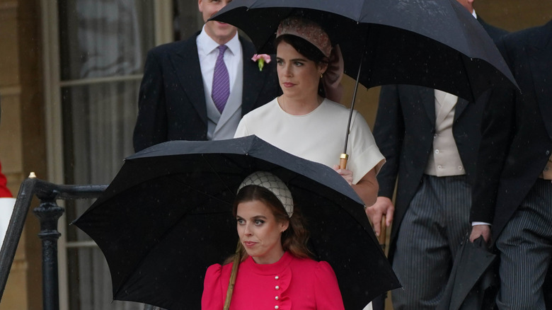 Princess Beatrice and Princess Eugenie walking under umbrellas