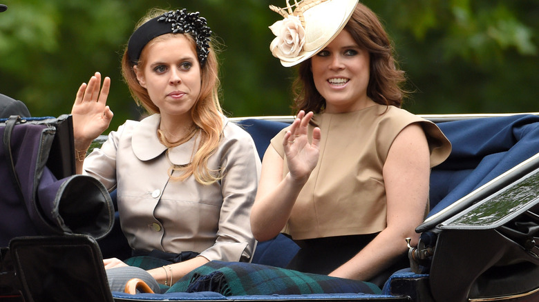 Princess Beatrice and Princess Eugenie waving while riding in back of car