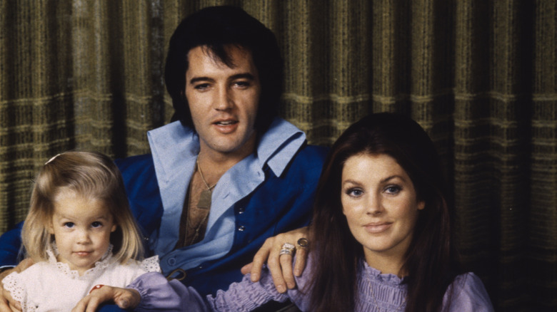 (l-r): Lisa Marie Presley, Elvis Presley, and Priscilla Presley sitting and smiling at the camers