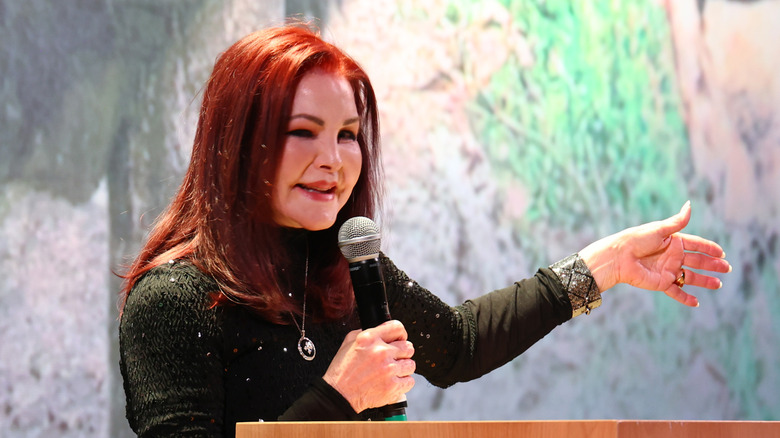 Priscilla Presley smiling while holding a microphone