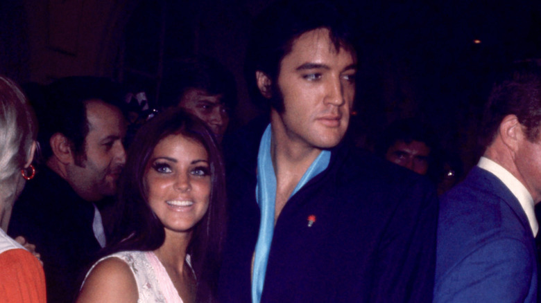 (l-r): Priscilla Presley and Elvis Presley smiling at an event