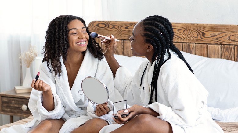 Two woman putting on makeup