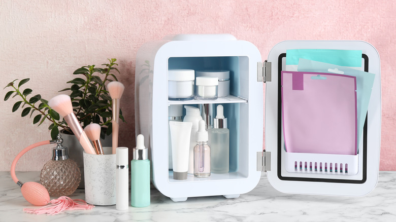 Beauty fridge next to makeup brushes and perfume bottle 