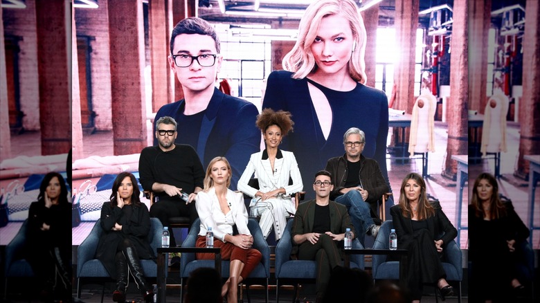 Project Runway judges posing in front of photo of Karlie Kloss and Christian Siriano