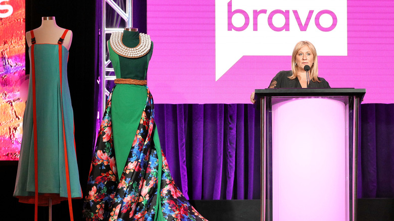 Woman stands at podium during Project Runway garment auction