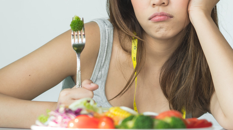 Woman looking unenthusiastic about vegetable salad