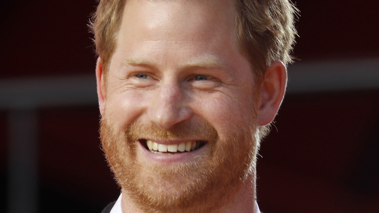 Prince Harry smiling with a microphone onstage
