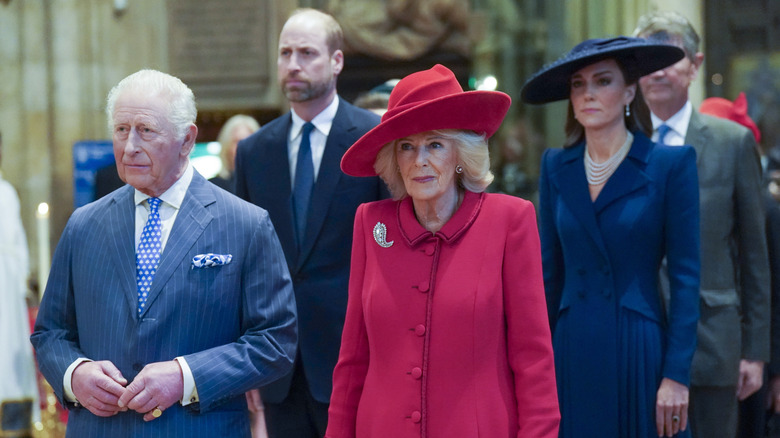 King Charles and Queen Camilla looking serious with William and Catherine, Prince and Princess of Wales standing behind them