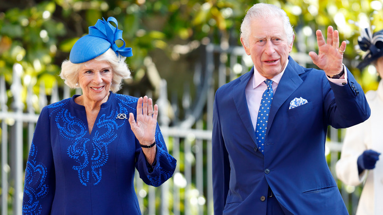 King Charles and Queen Camilla wearing blue outfits and waving