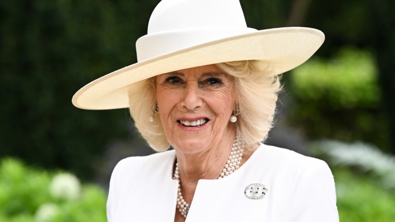 Queen Camilla smiling in a hat