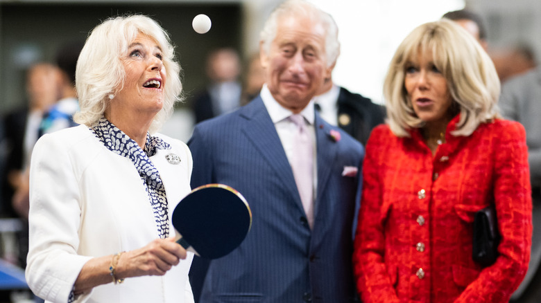 Queen Camilla playing ping pong while King Charles and Brigitte Macron watch