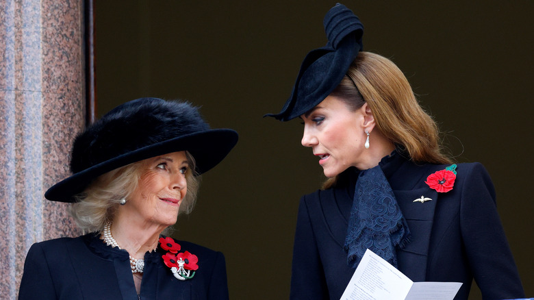 Queen Camilla smiling while Kate Middleton speaks to her
