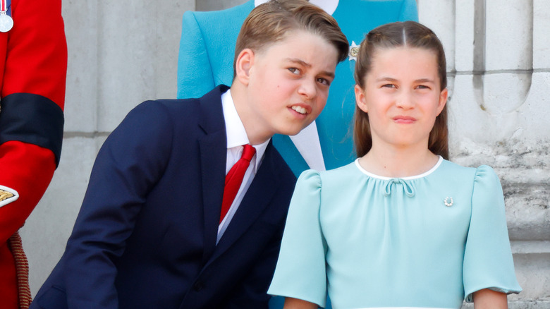 Prince George whispering to Princess Charlotte on the palace balcony