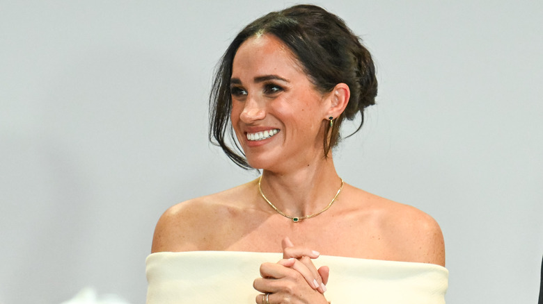 Meghan Markle smiling off-the-shoulder white gown