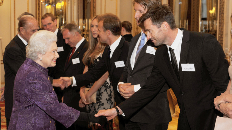 Queen Elizabeth II shakes hands with Hugh Jackman at Buckingham Palace in 2011