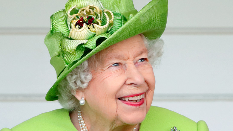 Queen Elizabeth smiling in a green hat