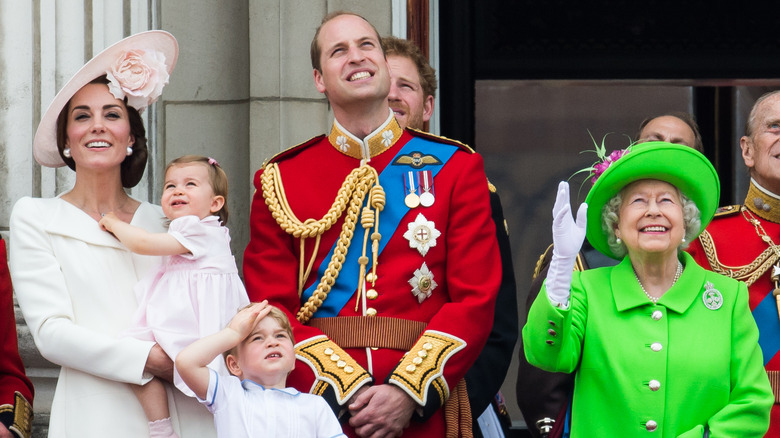 Kate Middleton holding Charlotte, Prince George, Prince William, and Queen Elizabeth smiling and waving at planes overhead