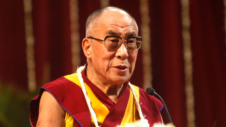 The Dalai Lama sitting and speaking into microphone