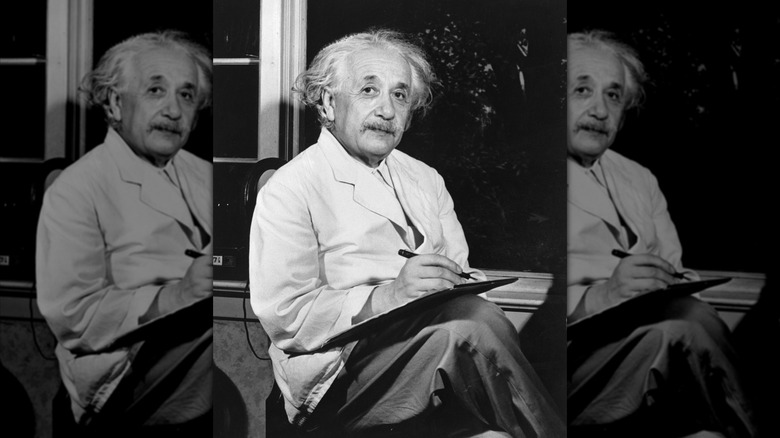 A photograph of an older Albert Einstein writing something down