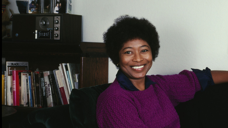 Alice Walker sitting on a couch smiling