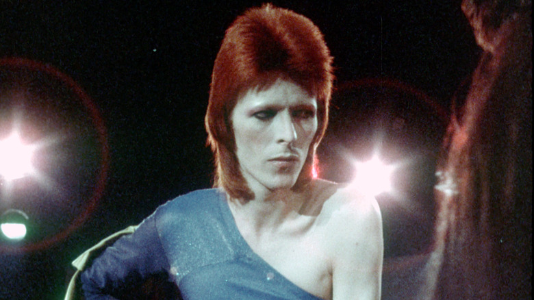 David Bowie performing onstage in a costume with spotlights behind him