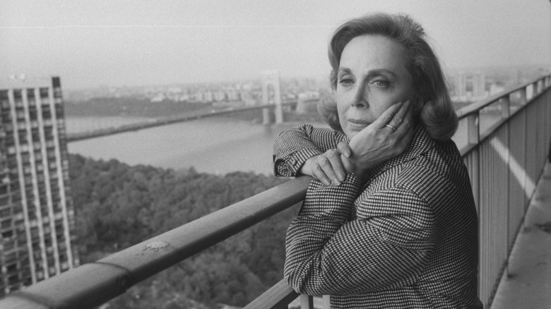Dr. Joyce Brothers in a checkered blazer holding her hand to her face while gazing out into the distance