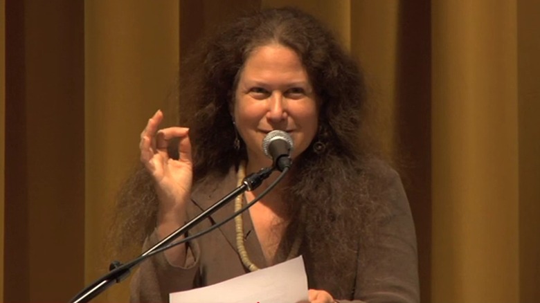 Jane Hirshfield smiling and talking in front of a microphone