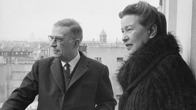 Jean-Paul Sartre and Simone de Beauvoir standing on a balcony together, looking out at the landscape