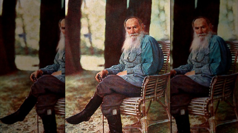 A portrait of Leo Tolstoy sitting on a chair around trees