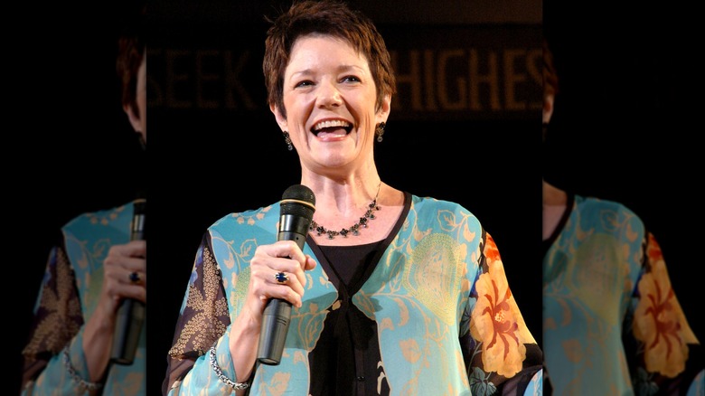 Sue Monk Kidd in colorful patterned shirt speaking into microphone