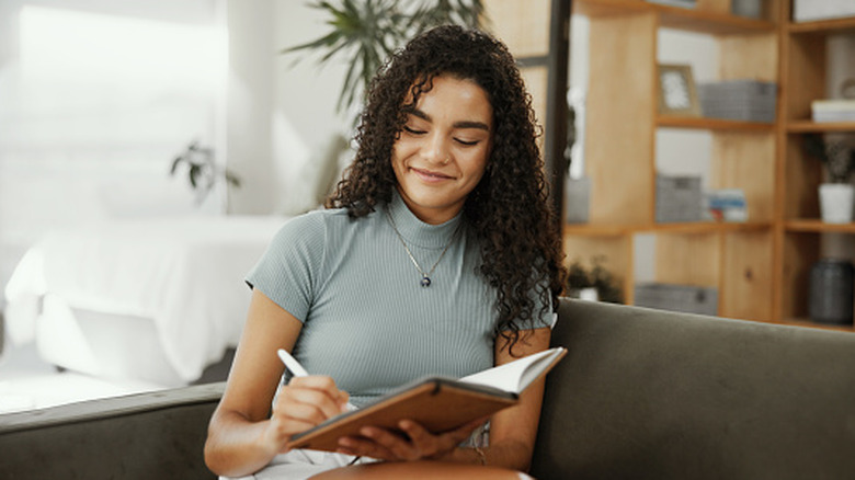 A woman writing in her journal with a smiling face