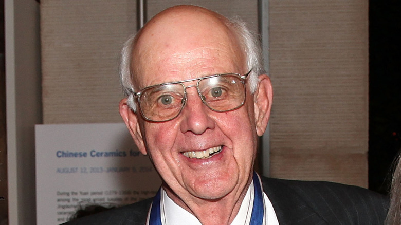 Wendell Berry smiling in glasses and a white shirt