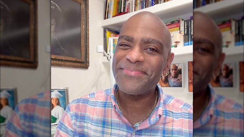 Antthony Mark Hankins smiling at home in a pink, blue, and white shirt.