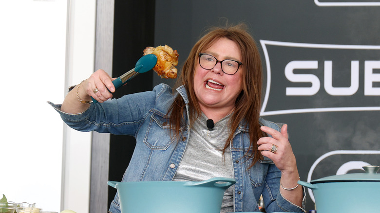 Rachael Ray holding up a piece of chicken with a tongs
