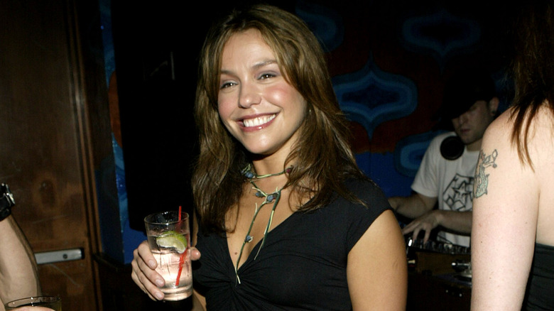 Young Rachael Ray holding a drink in a bar and smiling